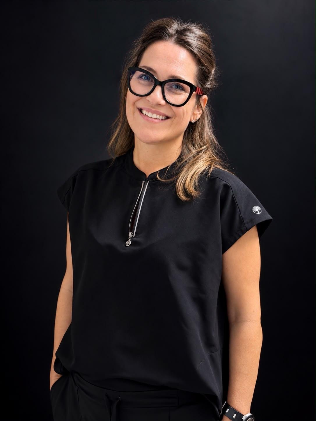 Retrato de la Dra. Nuria García sonriendo, con gafas y uniforme negro.